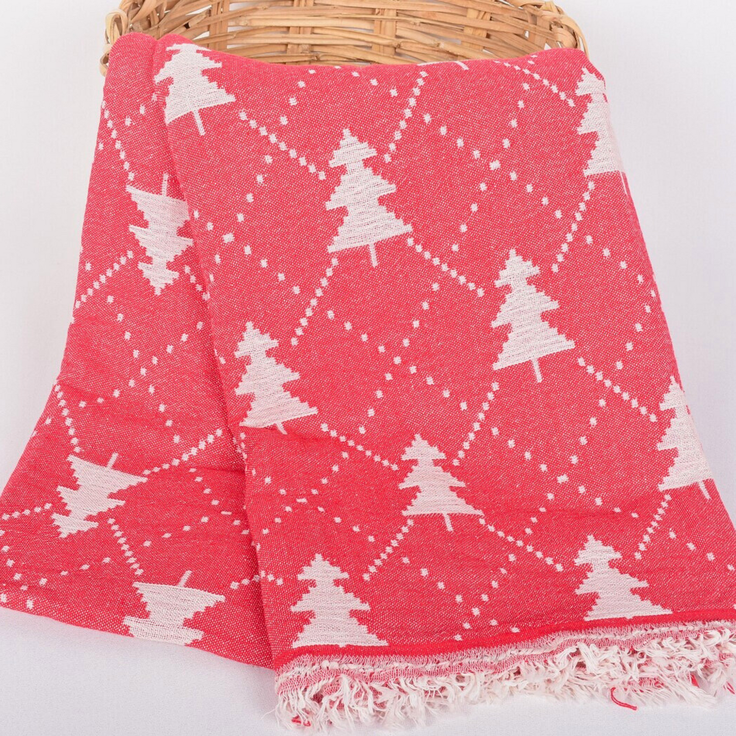 Red CHRISTMAS Throw Blanket with white Noel tree patterns draped over a wicker basket