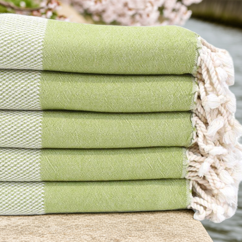 Stack of folded DENIZLI Turkish Bath Towels in green with spring flowers
