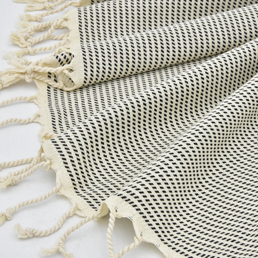 Black and white patterned Turkish towel with tassels on a light background