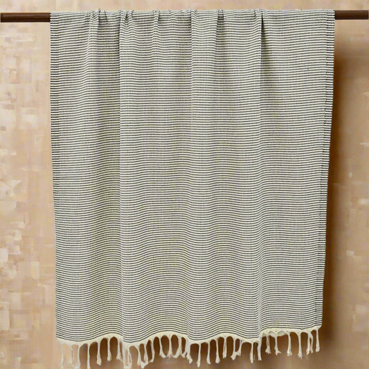 Black and white patterned Turkish bath towel with tassels on a light background