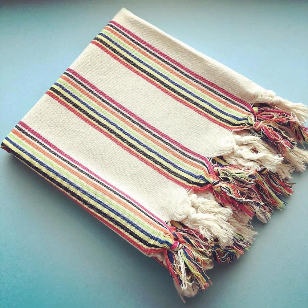 Folded RAINBOW Turkish Towel on blue background
