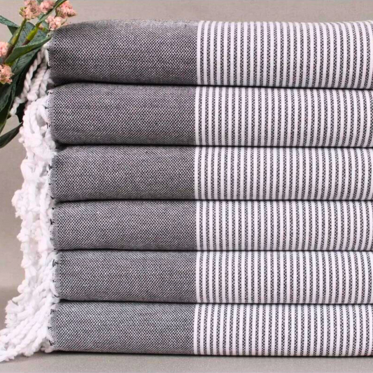 Folded PINSTRIPE Turkish Kitchen Towels stacked atop each other, complemented by pink flowers on a muted background