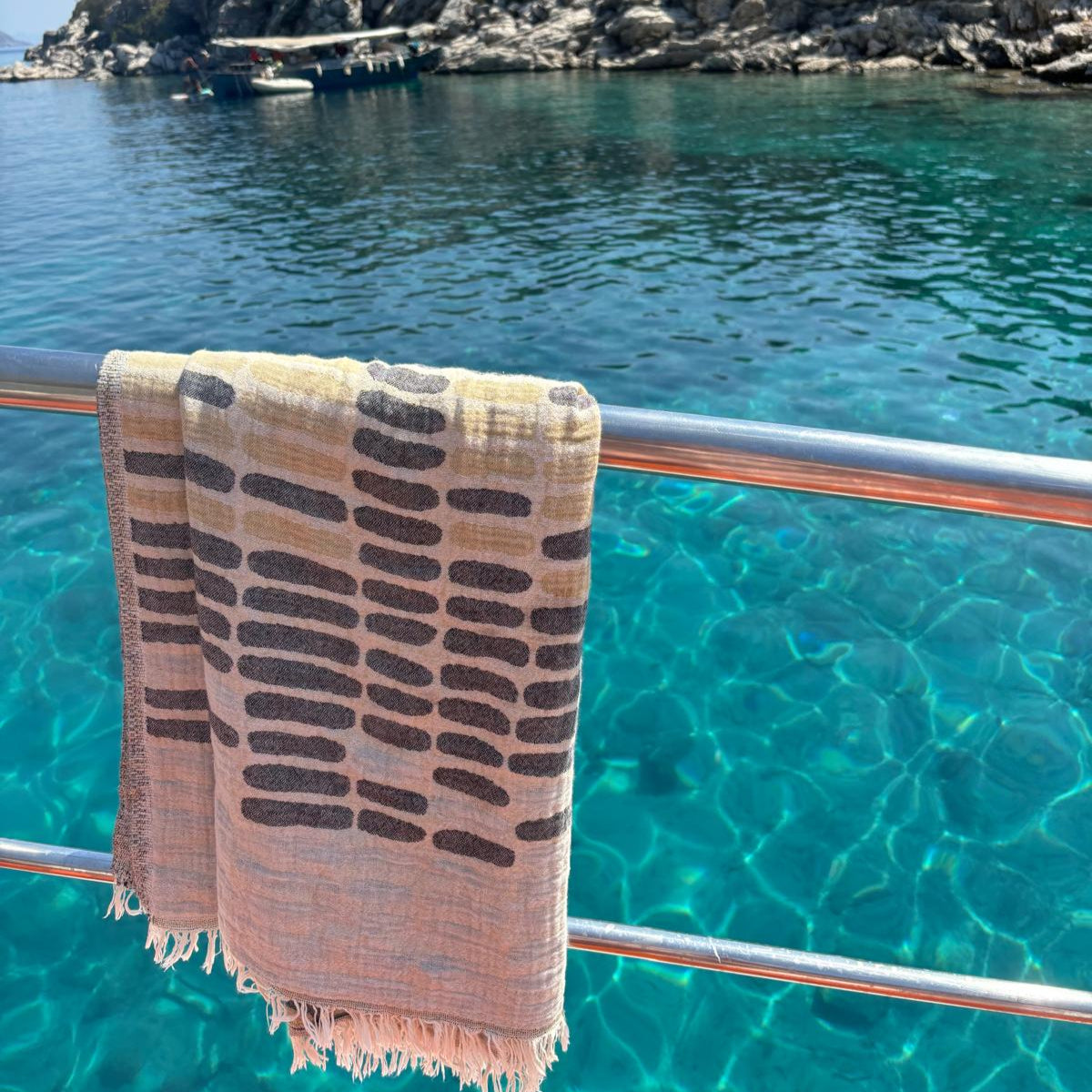 WAVES Turkish Towel with grey and beige pattern hanging on boat railing over turquoise Turkish Mediterranean sea