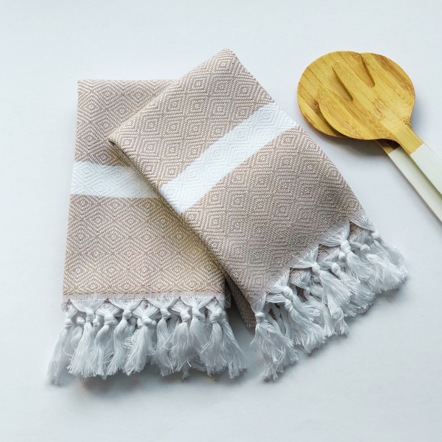 Folded beige Turkish Kitchen Towels next to wooden salad servers