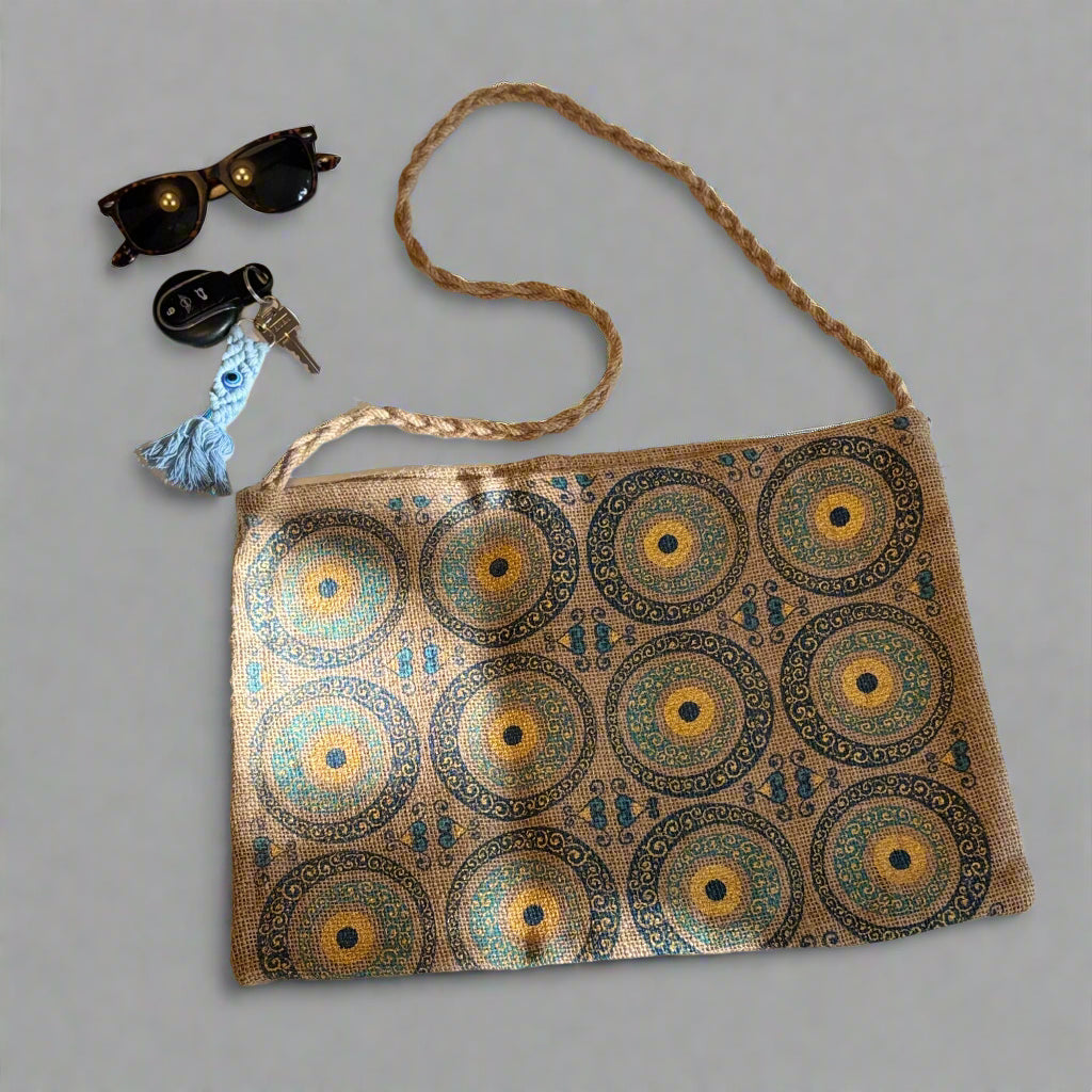 Turkish evil eye patterned jute tote bag with long strap next to sunglasses and keys on a light background
