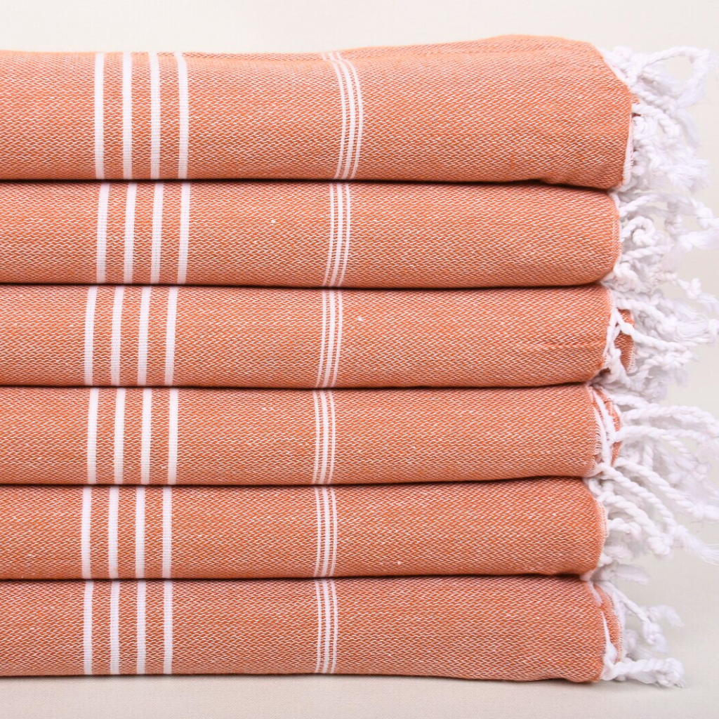 Stack of folded CLASSIC Turkish Towels in terracotta with white stripes & white hand-tied knots