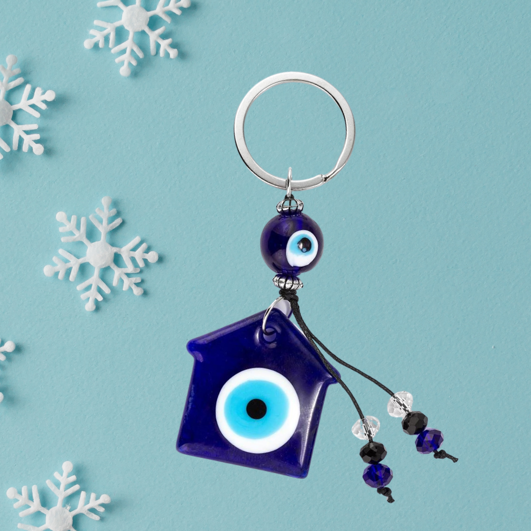 NAZAR Lucky Eye House Keychain with blue evil eye beads on a light blue background with festive snowflakes