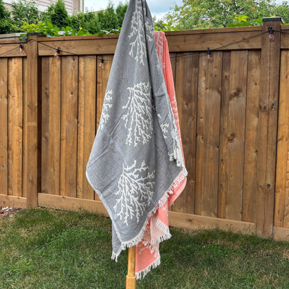 Grey Turkish towel with white coral patterns draped over a wooden structure outdoors