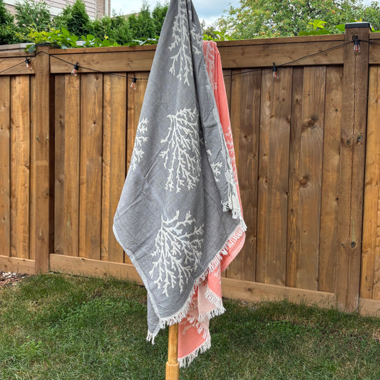 Grey Turkish towel with white coral patterns draped over a wooden structure outdoors