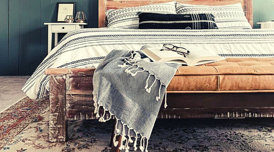 Black/grey Turkish towel used as a throw blanket on a leather bench in bedroom