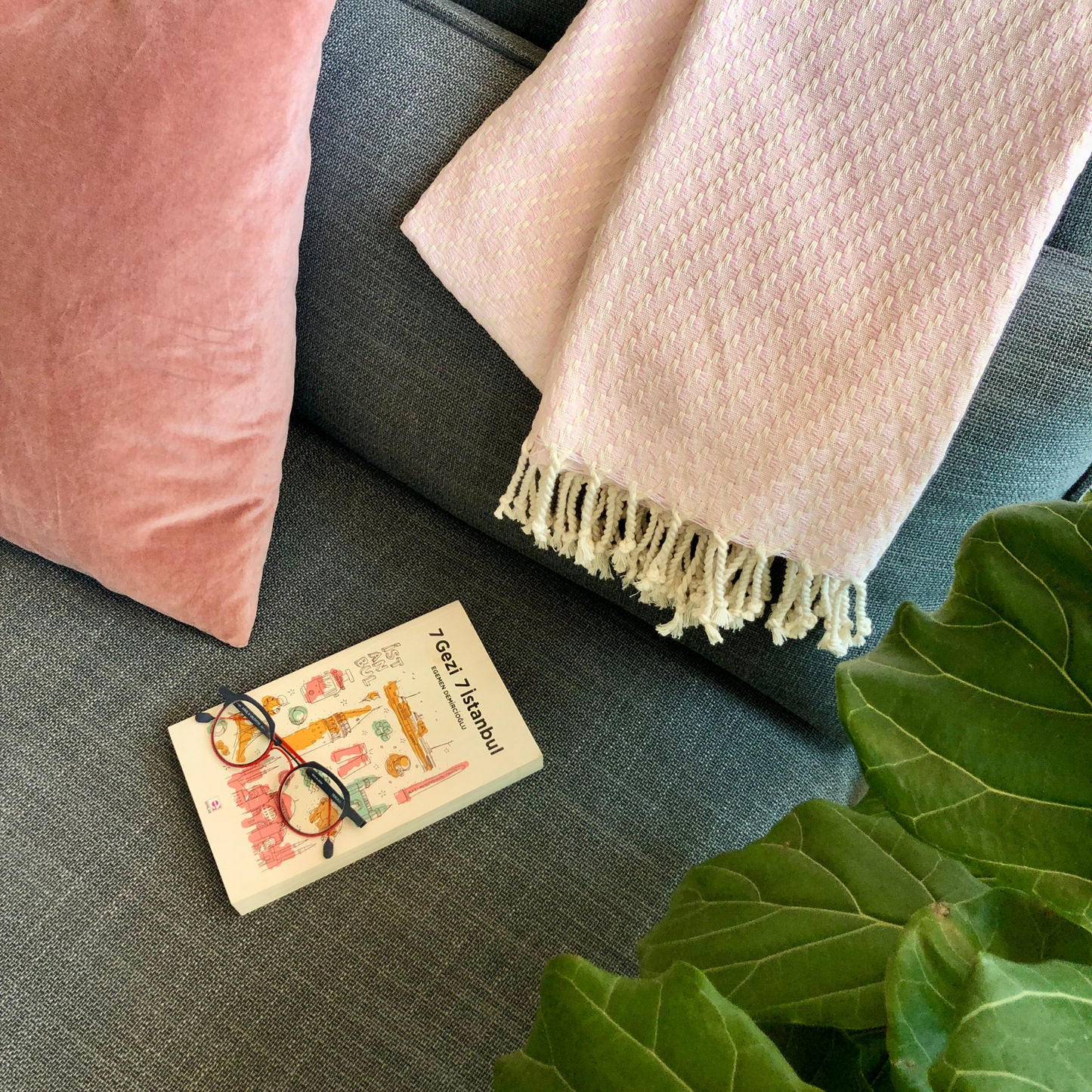 ISTANBUL Throw on grey sofa with pink pillow, Istanbul book and fiddle-leaf fig plant