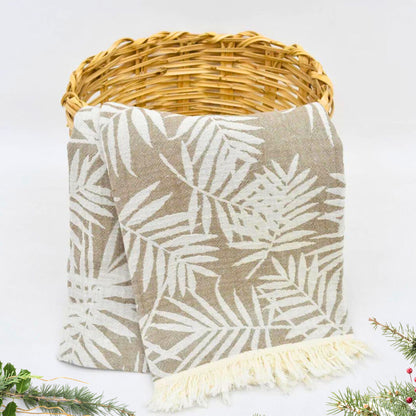 Brown Turkish towel with leaves pattern hanging from a basket, used as a cozy throw blanket with Christmas tree ornaments 