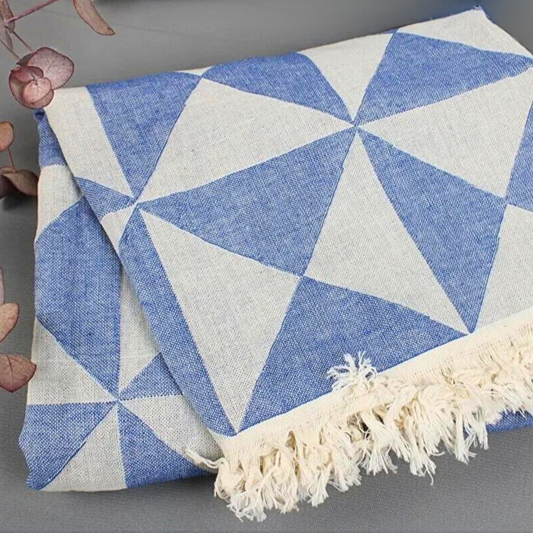 Close-up of MOSAIC Turkish Towel displaying its denim blue triangles pattern with dried foliage on one side