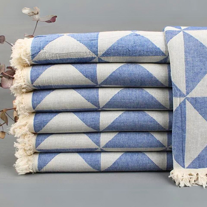 Stack of folded MOSAIC Turkish Towels in alternating denim blue and white geometric patterns with tassels on the end