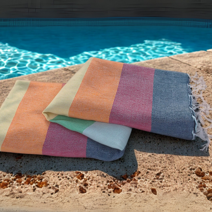 RAINBOW Turkish Towel with colourful stripes folded poolside on stone deck
