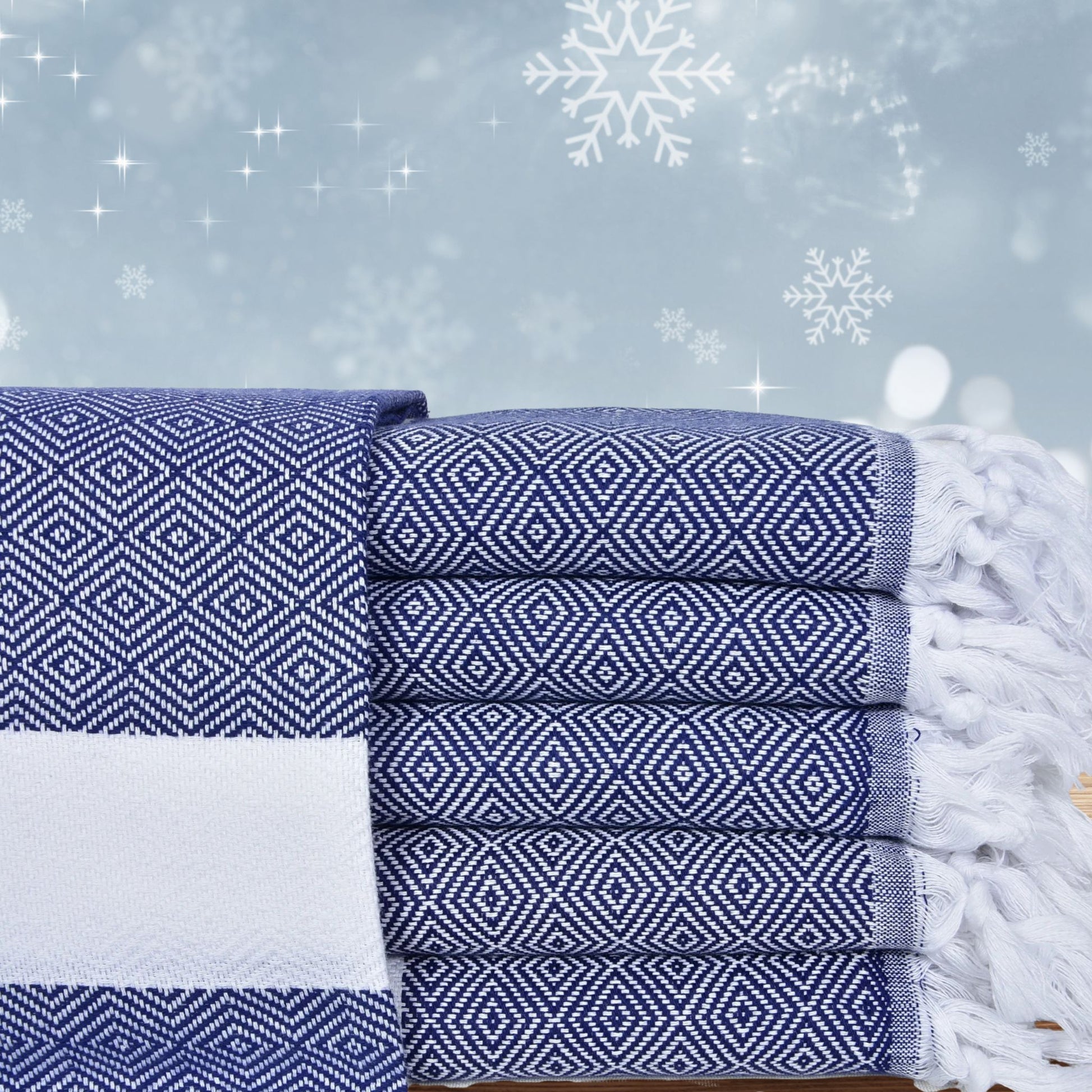 Stack of navy patterned Turkish towels with festive snowflakes and stars in the background