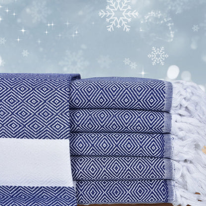 Stack of navy patterned Turkish towels with festive snowflakes and stars in the background