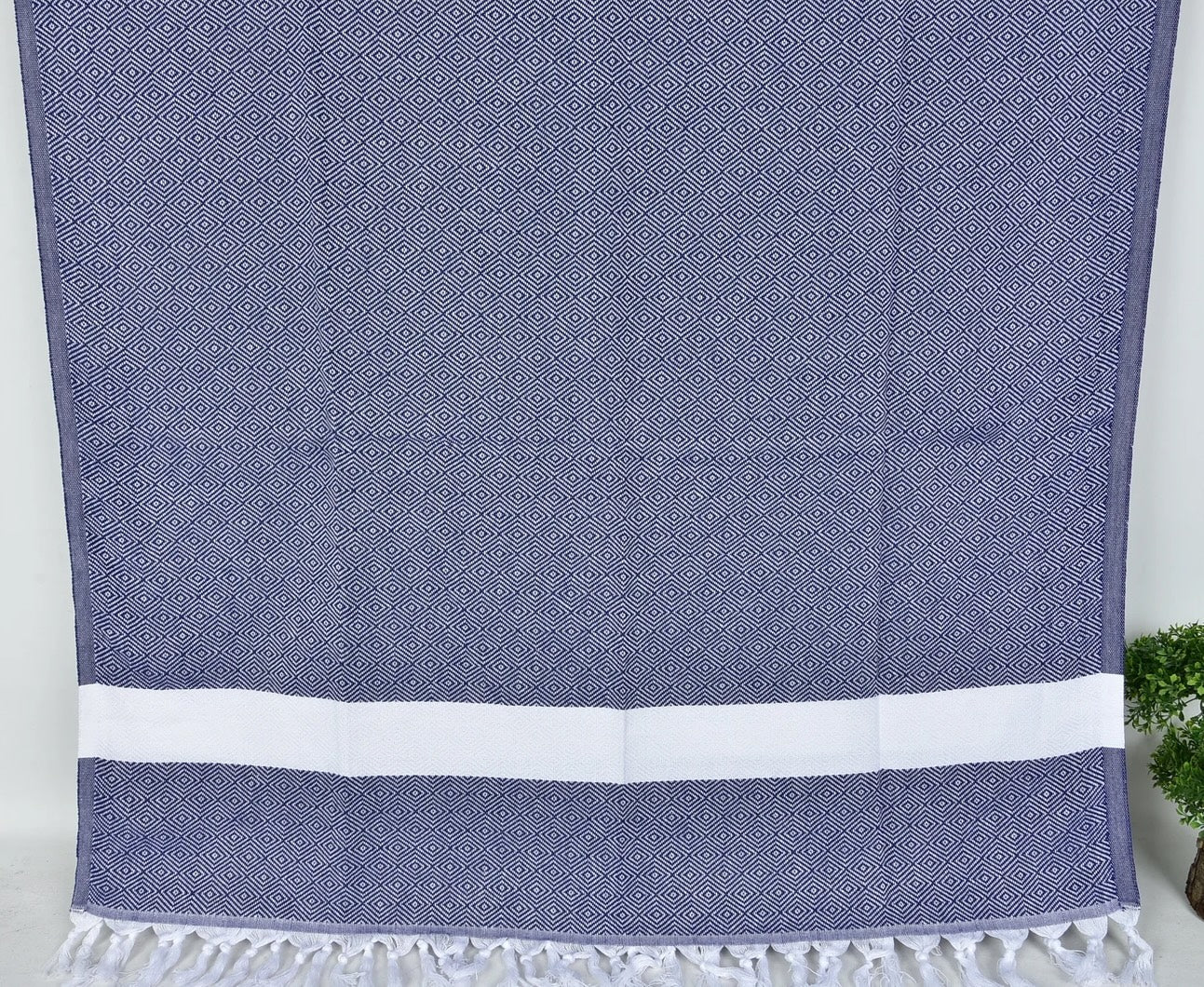 Navy blue SULTAN Turkish towel with white stripes on a light gray background