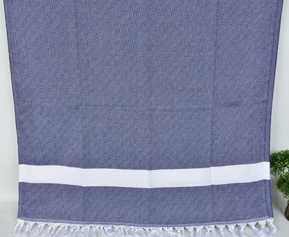 Navy blue SULTAN Turkish towel with white stripes on a light gray background