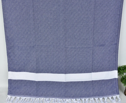 Navy blue SULTAN Turkish towel with white stripes on a light gray background