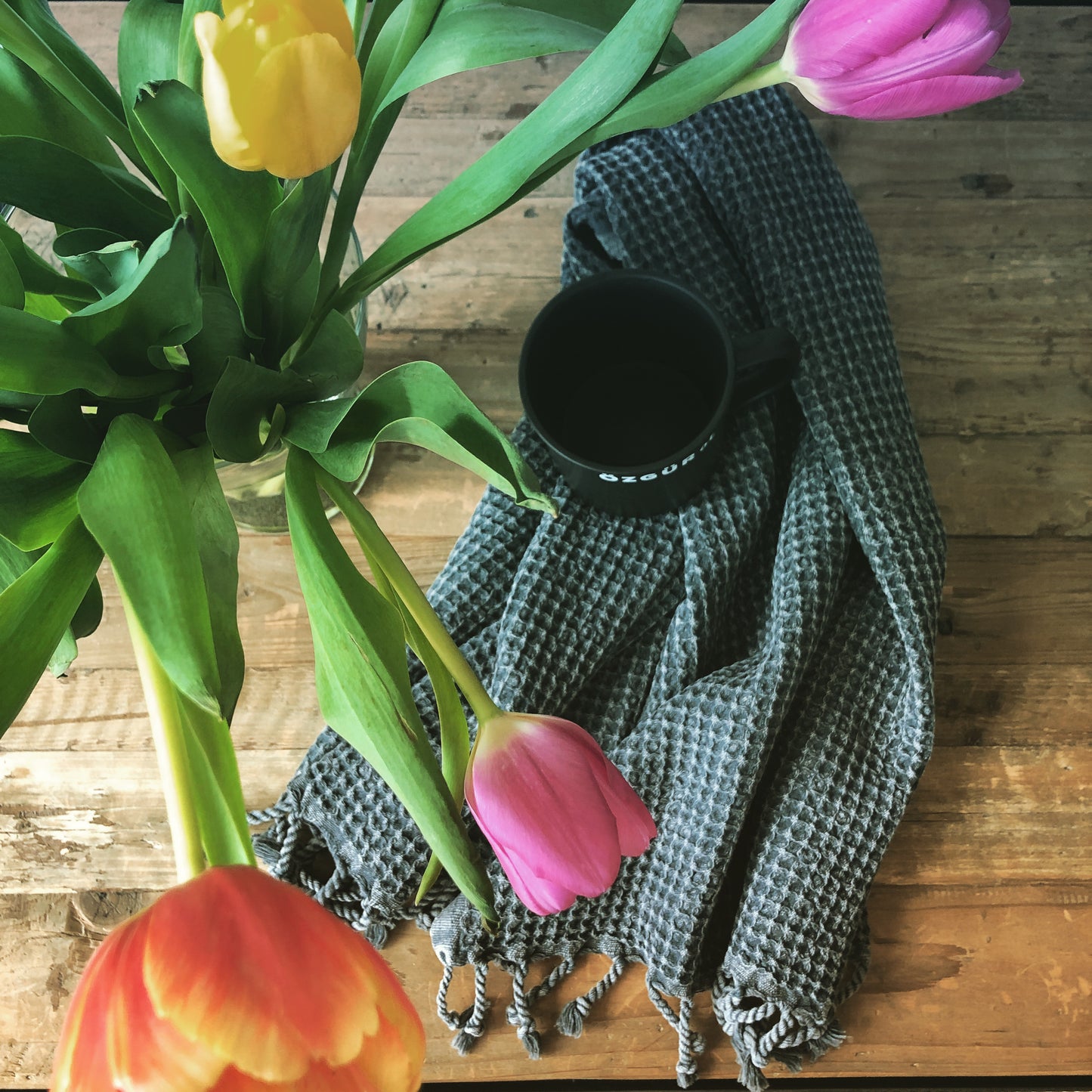 Black WAFFLE Turkish Hand Towel with a black coffee mug and colourful tulips