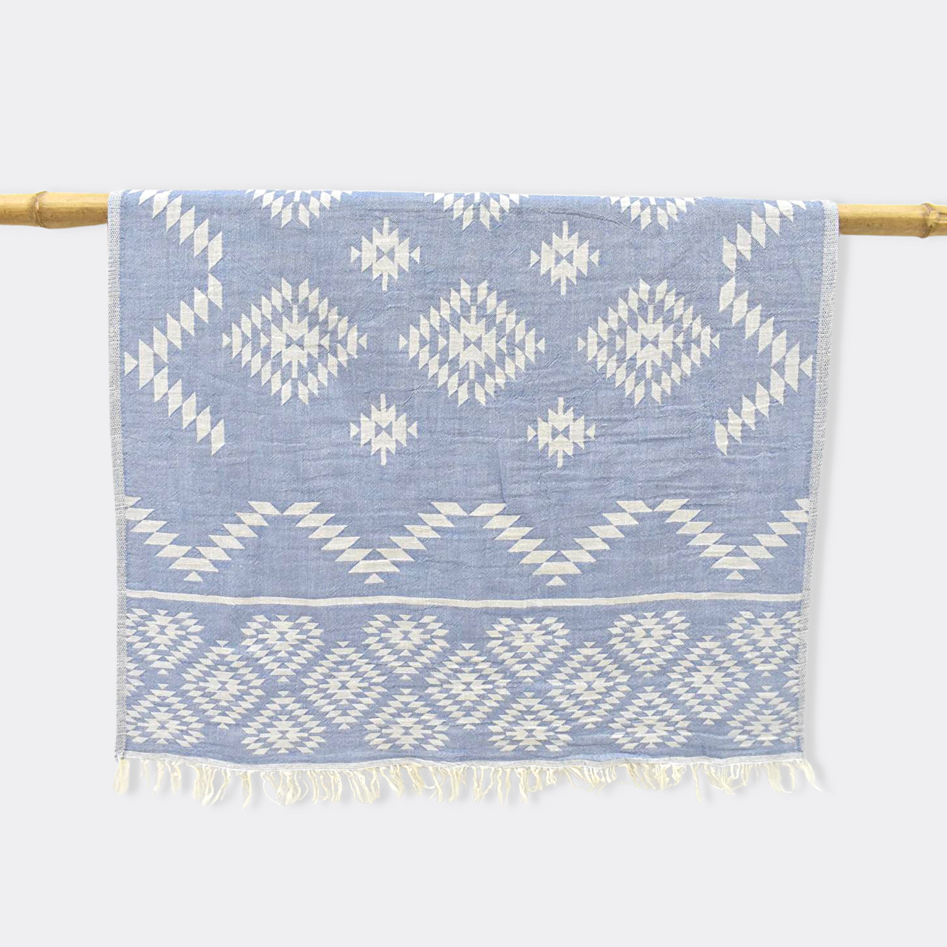 Light blue KILIM Double-Sided Turkish Hand Towel hanging from bamboo stick