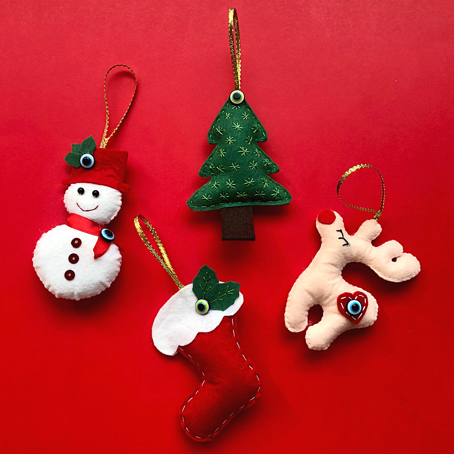Felt Christmas ornaments featuring a snowman, tree, stocking, and reindeer, each adorned with a protective blue 'nazar' evil eye bead, set against a red background