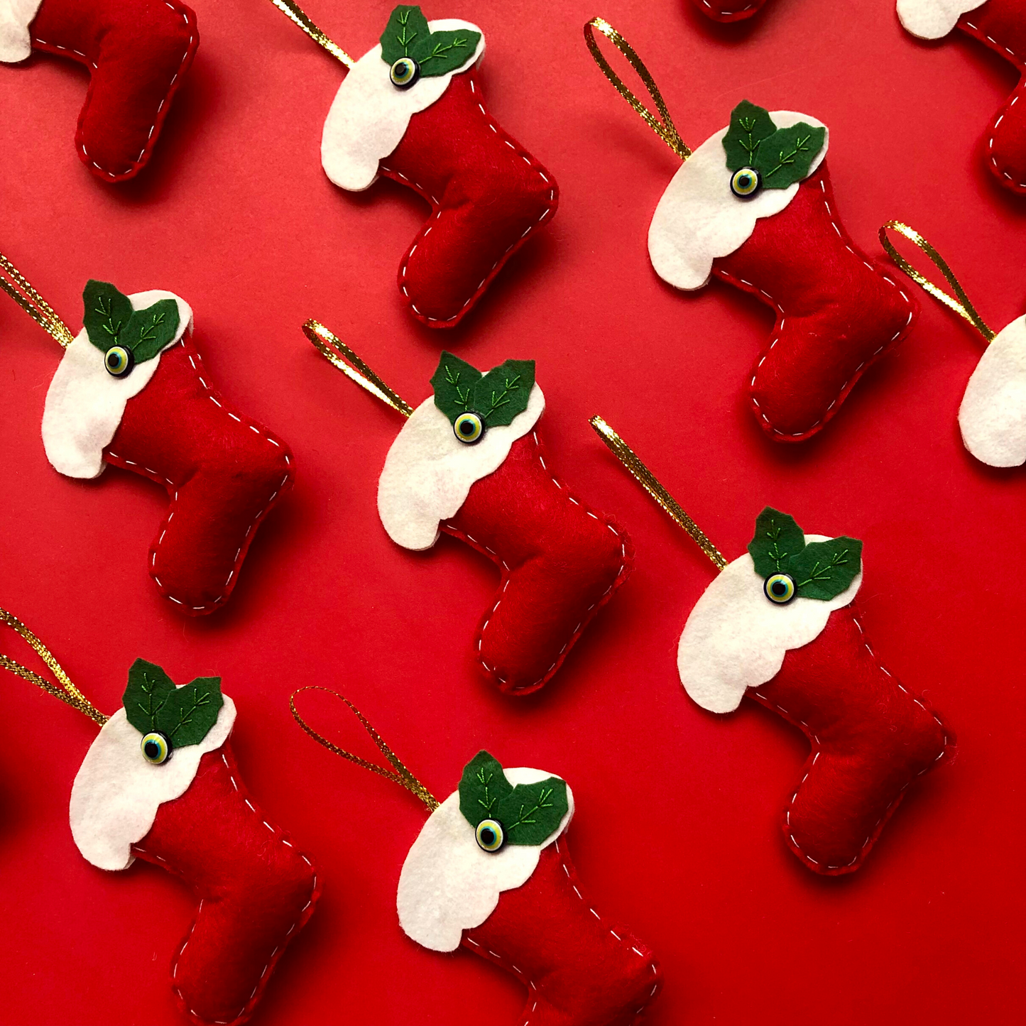 Red and white Christmas stockings with evil eye beads on festive red background