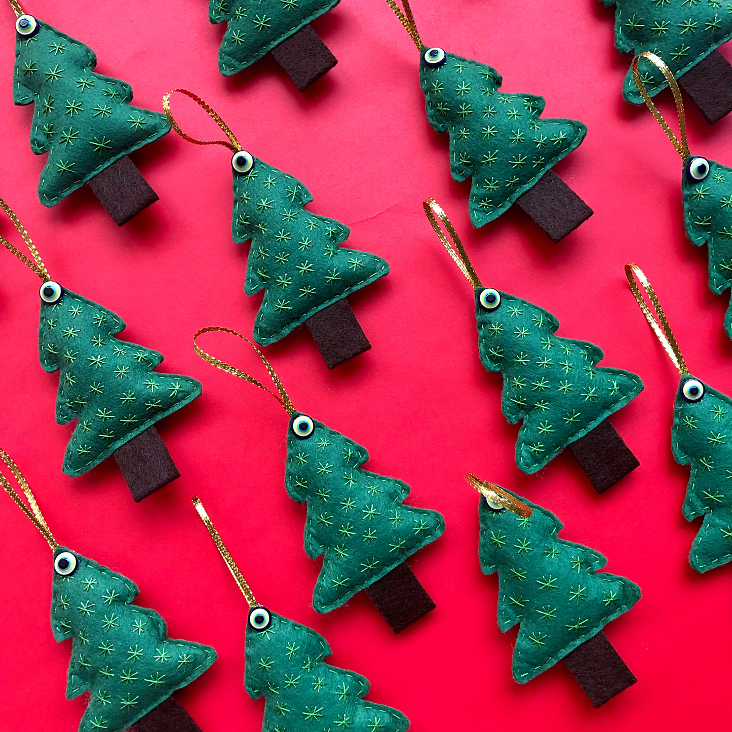 Christmas trees with evil eye beads on festive red background