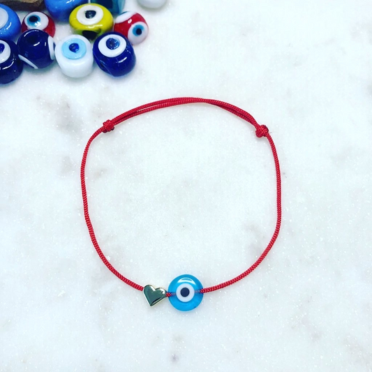 NAZAR HEART Evil Eye Bracelet with red cord next to colourful evil eye beads