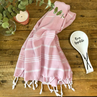 Soft pink Turkish kitchen/hand towel with white stripes next to pink candle, plants and spoon rest